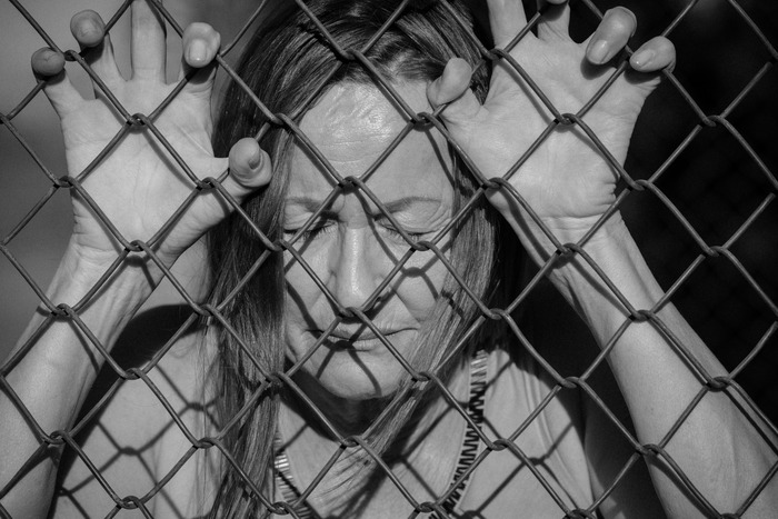Photo of distressed woman prisoner holding fence